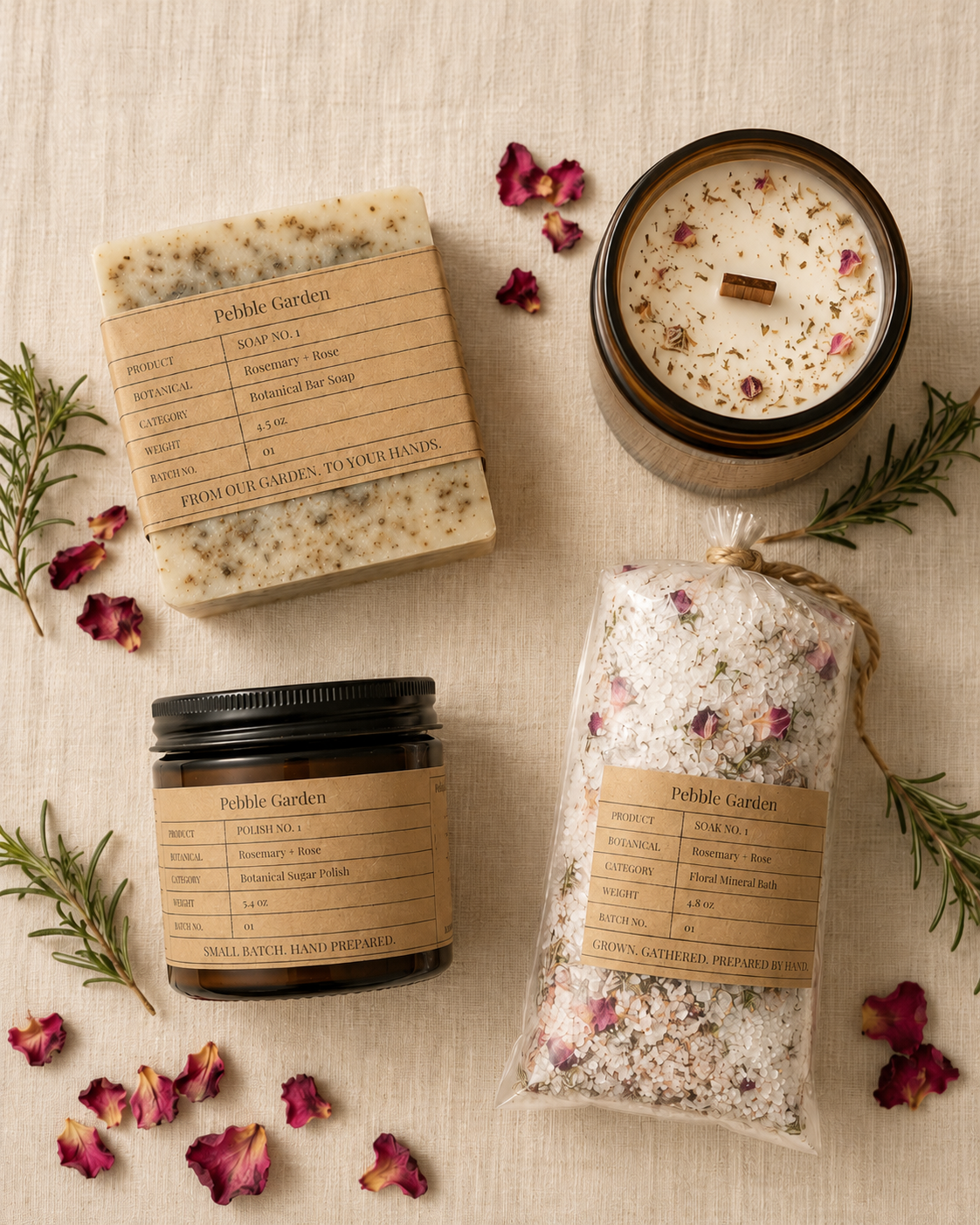 Pebble Garden First Harvest collection — soap, candle, polish, and mineral soak with rosemary and rose petals on linen